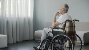 A man sits alone in a wheelchair, wondering how to report suspected nursing home abuse in Georgia.