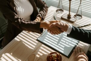 Attorneys shake hands, showing you can settle a nursing home abuse case out of court.