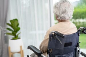 An older woman in a wheelchair sits alone and wonders what the lowest-rated nursing homes in Rosewell are.