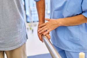 A caregiver gently holds an older adult's hands at one of the lowest rated Macon-Bibb nursing homes.